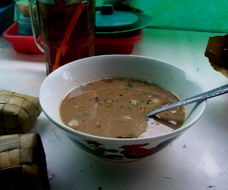 Seporsi Coto Makassar dengan kuah coklat yang gurih. Biar kenyang, bisa minta dipotongkan ketupat.