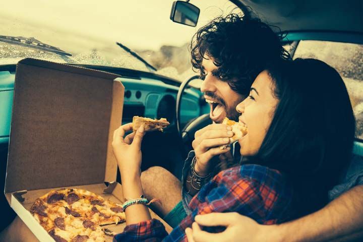 Couple eating pizza in retro car