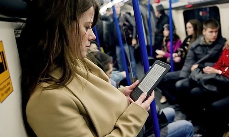 Woman with e-reader on tube train