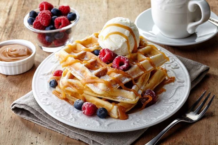 Plate of belgium waffles with ice cream, caramel sauce and fresh berries