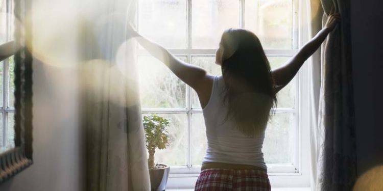 woman opening curtains in the morning