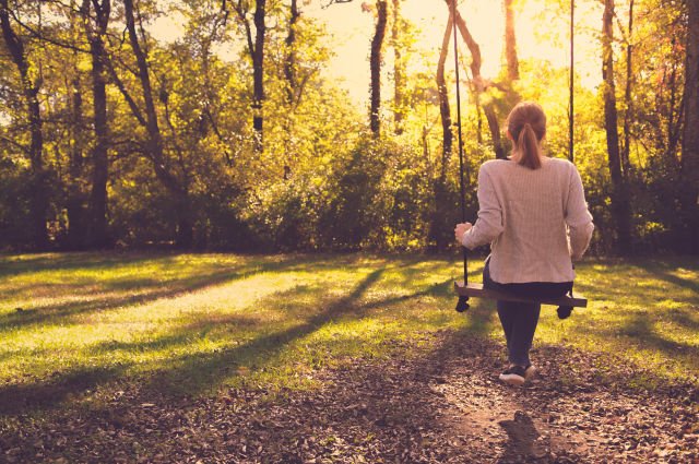 Girl-Sitting-Alone-On-Swing-In-Autumn