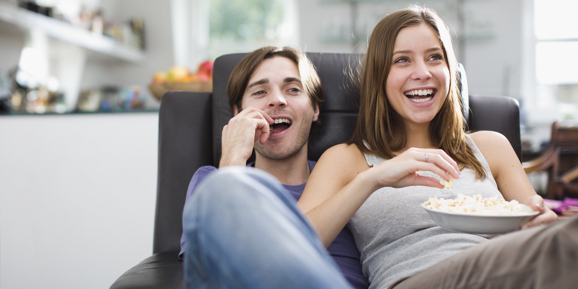 Couple watching television and eating popcorn