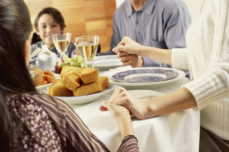 Portrait of a family saying grace before eating dinner --- Image by © Royalty-Free/Corbis