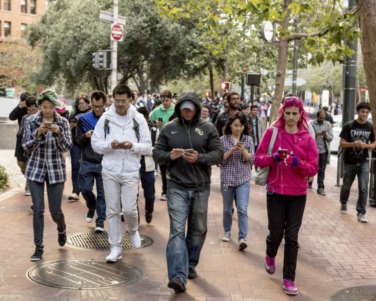 People walk up Market Street playing Pokemon Go, an augmented reality game, during a Pokemon Go Pub Crawl in San Francisco, July 20, 2016. Pokemon Go has fast become a nationwide phenomenon, with millions downloading the game and playing it just about everywhere. (Jason Henry/The New York Times)