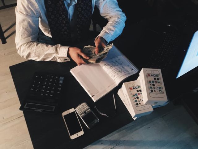 person-counting-money-with-smartphones-in-front-on-desk