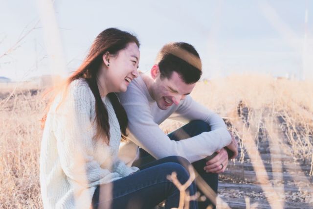 woman-in-white-shirt-beside-man-in-gray-long-sleeve-shirt-laughing-during-daytime