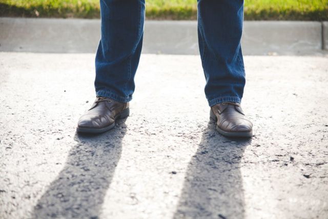 person-in-blue-jeans-and-brown-oxford-shoes-standing-near-grasses