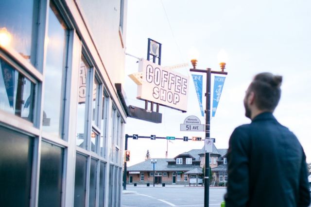 man-in-black-blazer-standing-in-front-of-coffee-shop