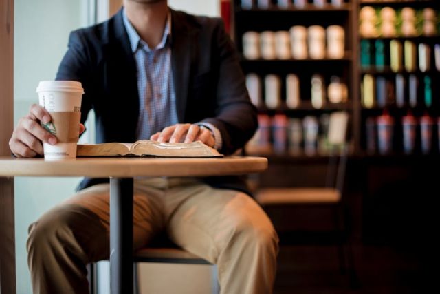 man-in-black-suit-holdin-starbucks-cup-near-book