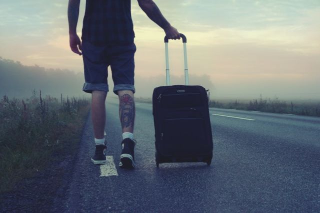 man-walking-on-the-road-holding-black-luggage