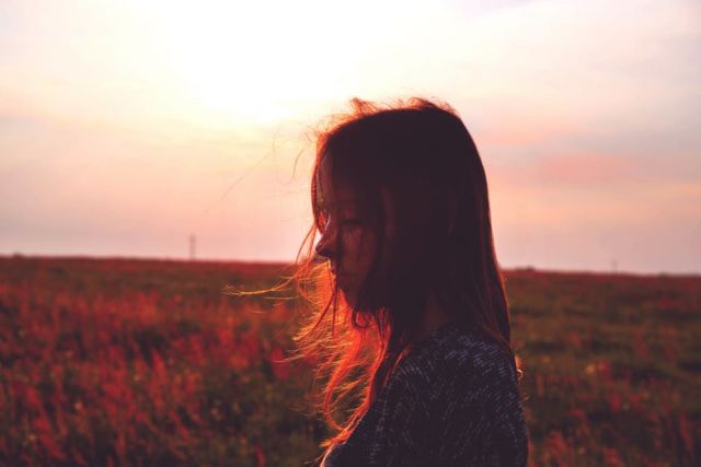 woman-standing-on-red-flower-field-during-daytime