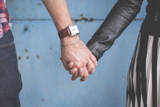 2-person-holding-hands-besides-blue-painted-wall