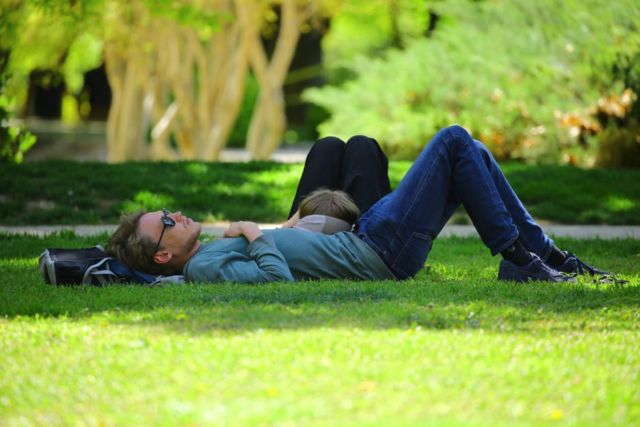 man-wearing-blue-long-sleeve-shirt-lying-on-ground-during-daytime