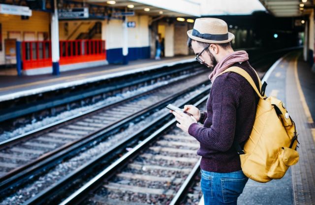 man-in-brown-hoodie-standing-in-front-of-train-railway