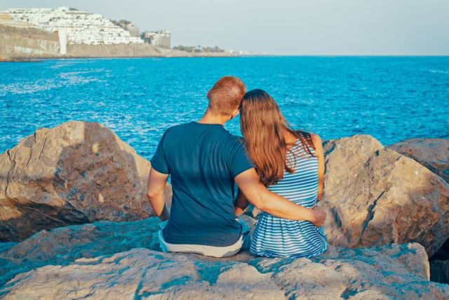 rear-view-of-couple-sitting-on-beach