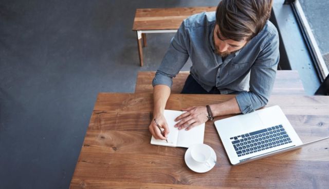 man writing blog post in coffee shop