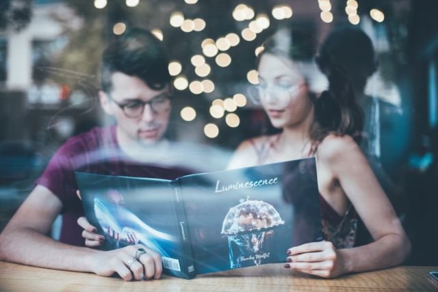 man sitting beside woman reading