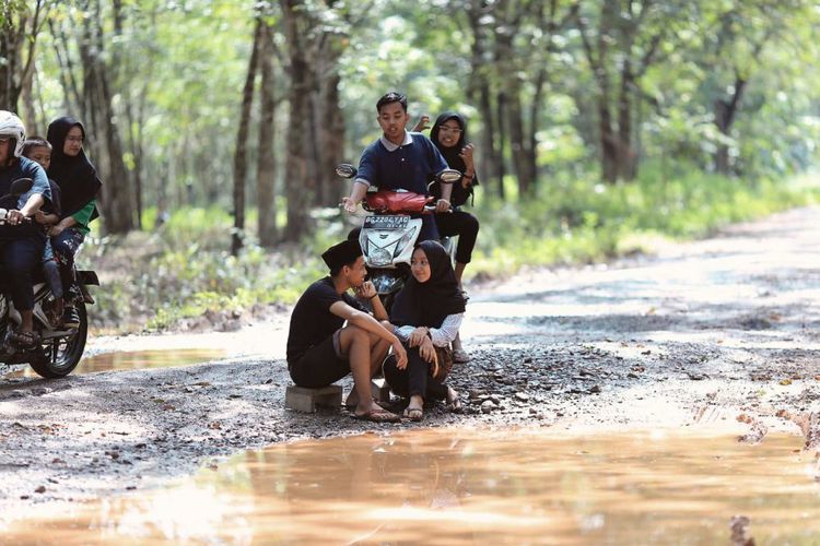 Protes Jalan Rusak dan Berlubang, Anak-anak Muda Berpose di Dalam Lumpur. Kritikan yang Efektif Nih!