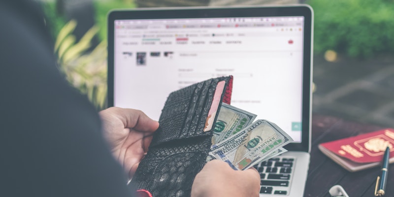  Person holding 10 US dollar banknote in front of gray