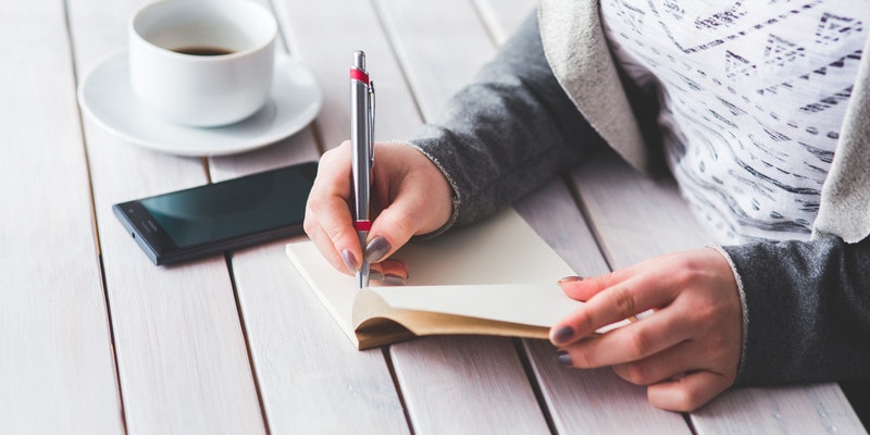 Womens hand using a pen noting on notepad